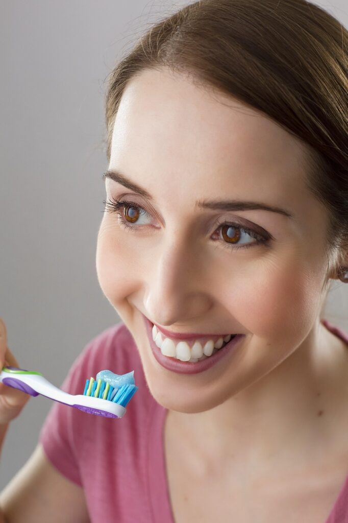 Smiling woman brushing her teeth at home