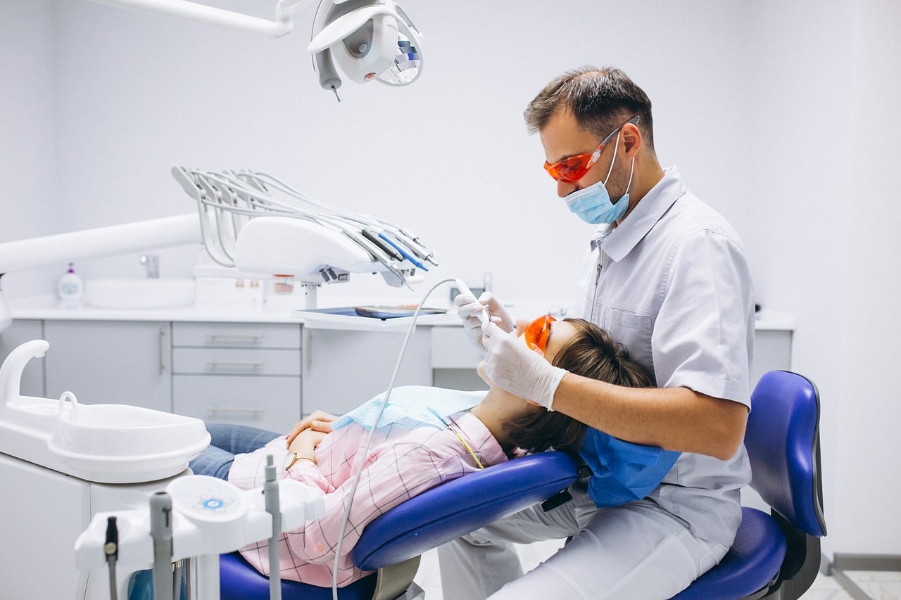 Dentist performing professional teeth whitening treatment on a female patient